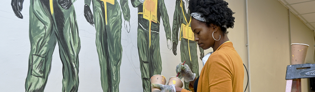 Woman painting military wall mural